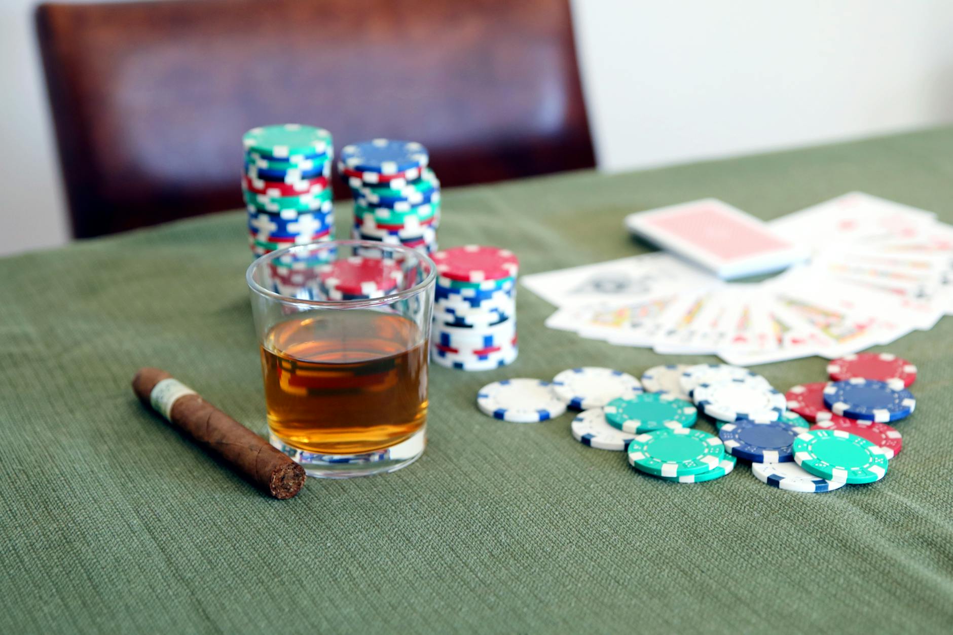 A poker table with chips, cards, whiskey, and cigar, creating a classic game night ambiance.
