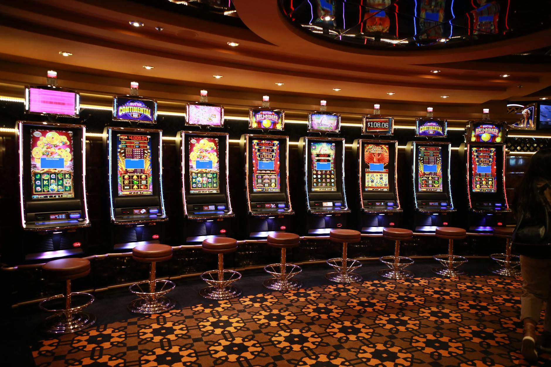 A row of luxury slot machines in a casino interior with plush stools, perfect for gaming enthusiasts