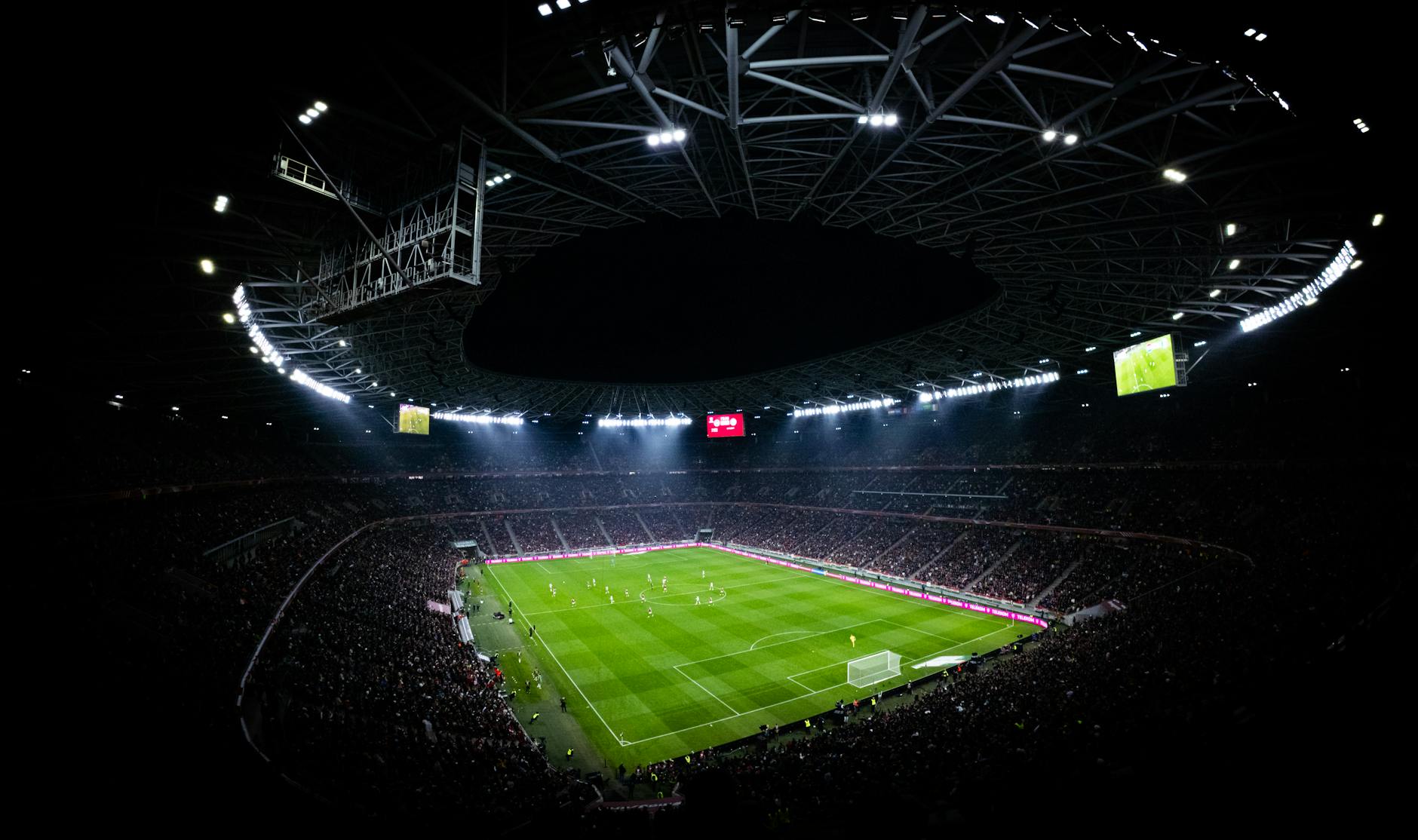 Aerial view of a night football match in Budapest. Illuminated stadium full of fans adds dramatic at